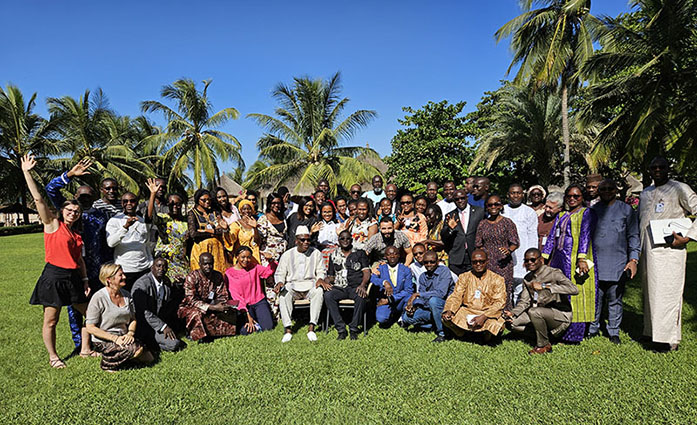 Afro-ACDx participants standing on grass, with trees on both sides and blue sky in the background