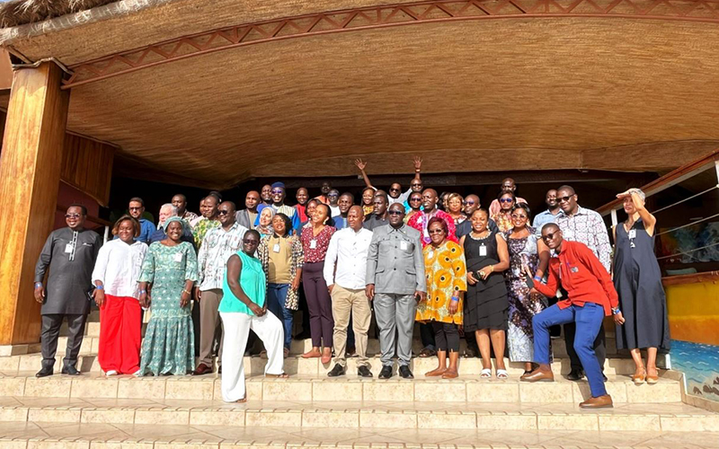 A group of Afro-ACDx participants stand on the steps at the entrance to a building in the centre of town.