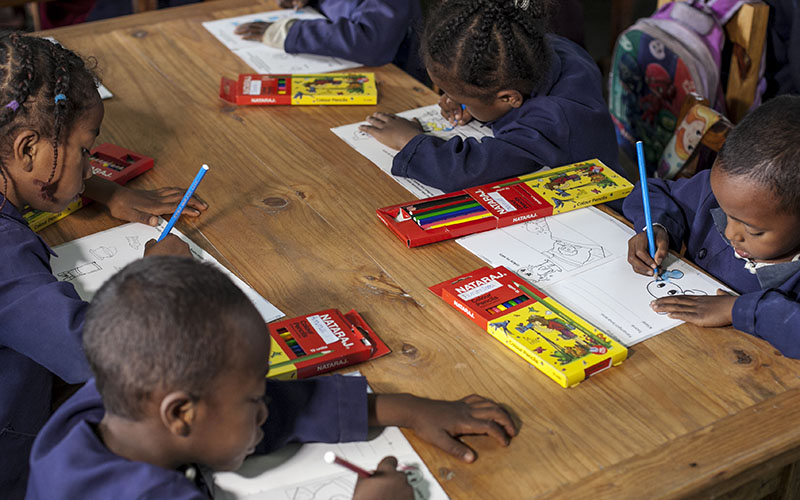 Enfants dessinant autour d’une table avec des crayons de couleur à Madagascar