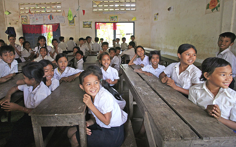 Enfants en uniforme assis à des pupitres dans une salle de classe au Cambodge