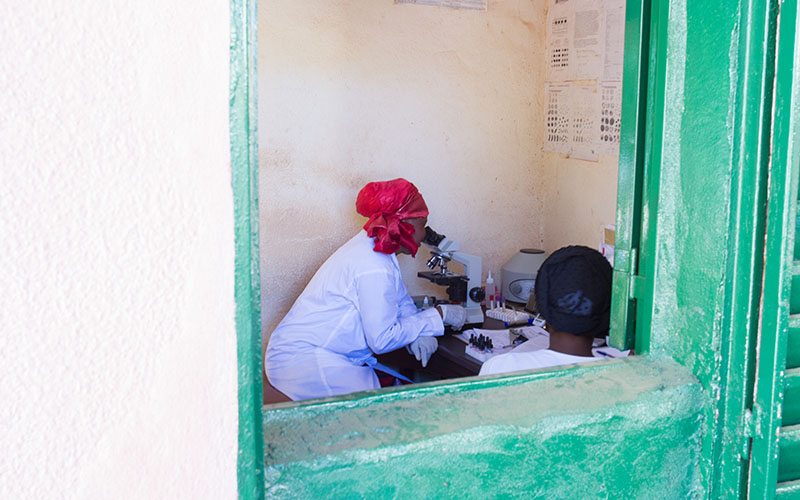 Professionnel de santé utilisant un microscope dans un laboratoire de santé communautaire au Mali 