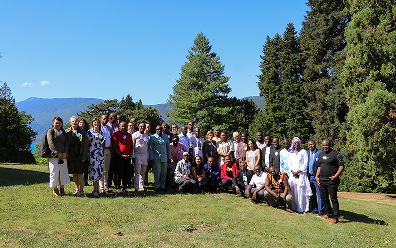 En extérieur, dans un parc arboré, un groupe d'une vingtaine d'individus pose debout.