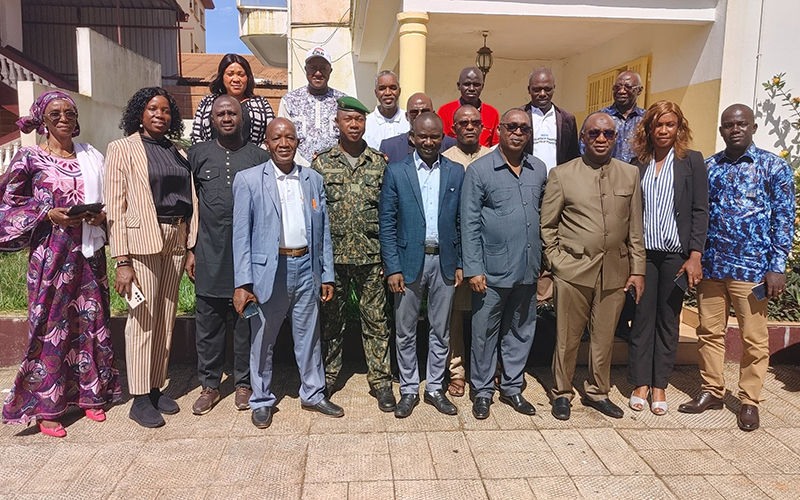 A l'extérieur d'un bâtiment se tient une dizaine de personnes debout.